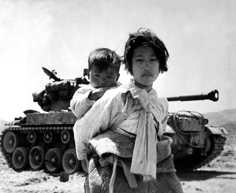 woman with child on her back in front of tank