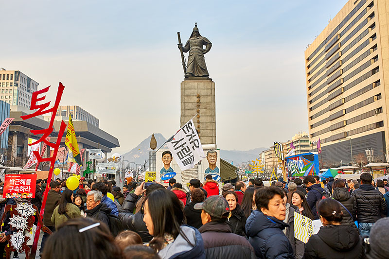 people in city square with statue