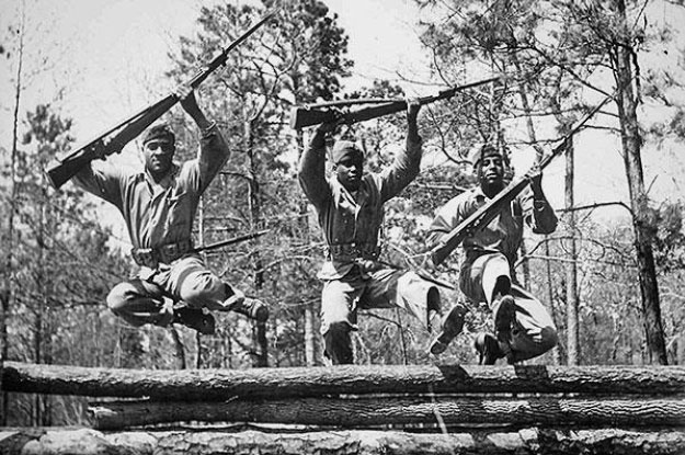 three soldiers with rifles jumping over wall