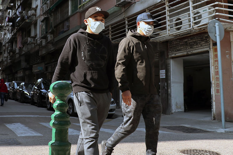 two men with masks on city street